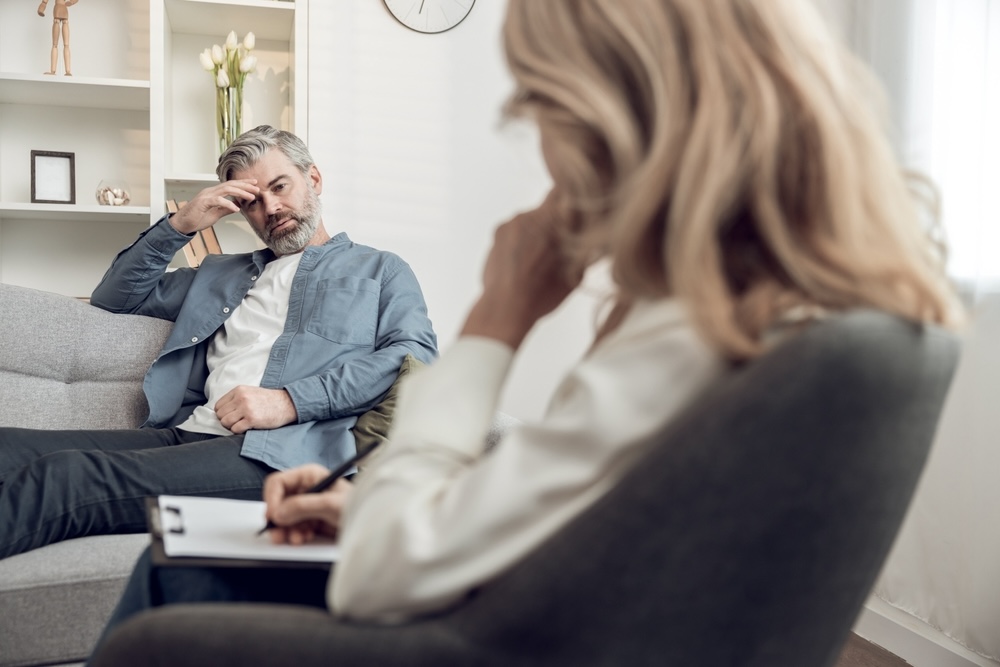 A troubled man suffering from substance abuse talking to a psychologist