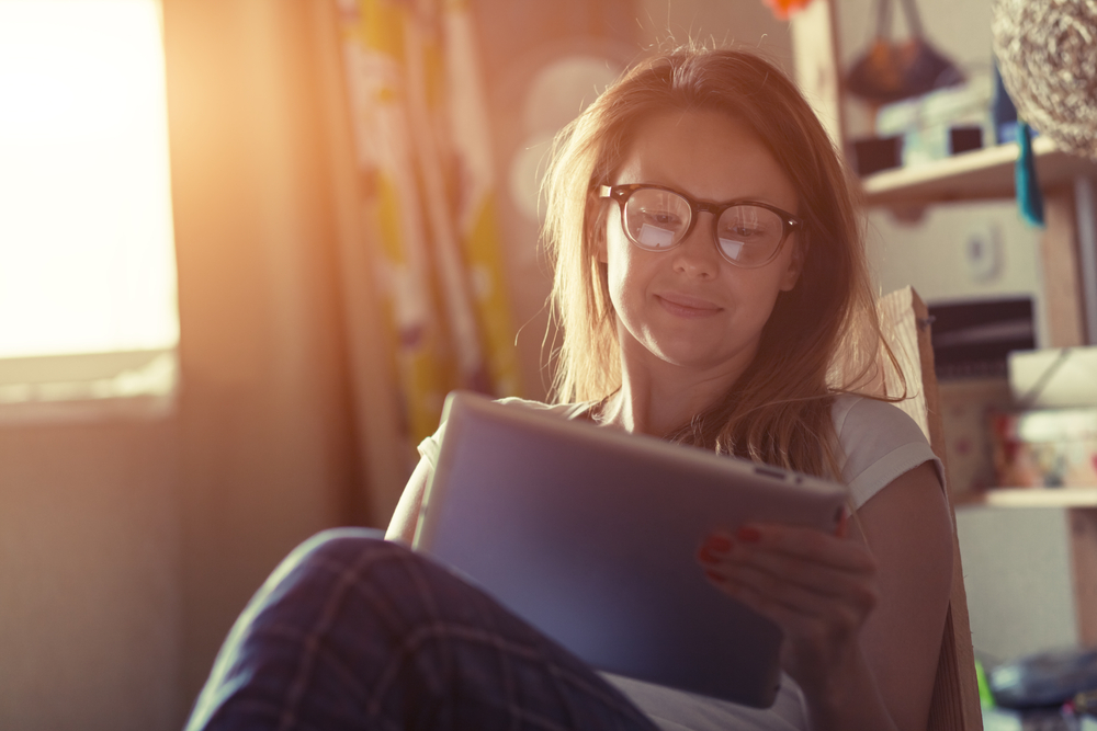 A woman wearing eyeglasses reading Thanksgiving addiction recovery quotes while sitting in a chair