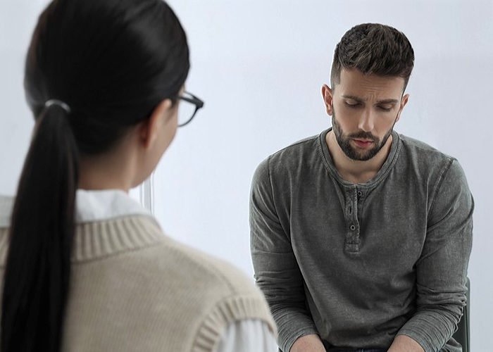 male patients looks sad in front of a therapist