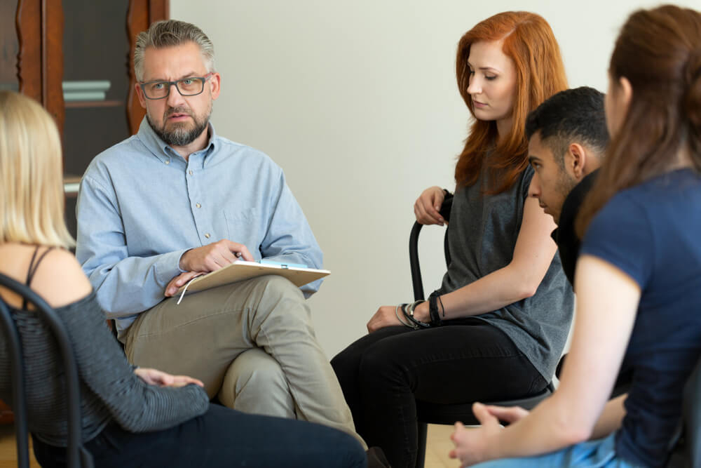 Therapist talking to a group of patients in a group session in a rehab center