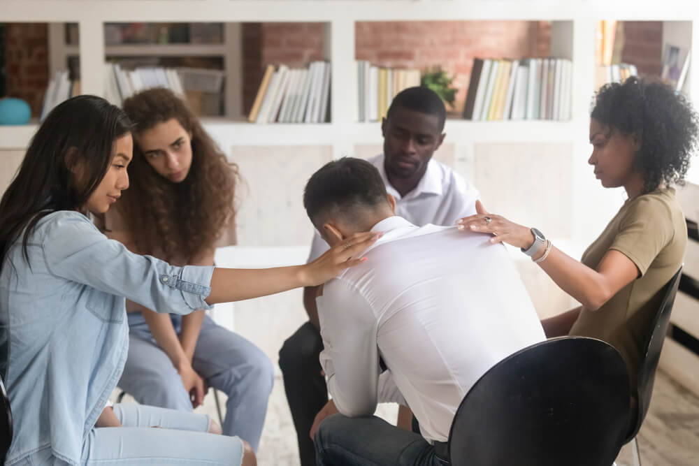 A troubled man consoling by his fellow patients