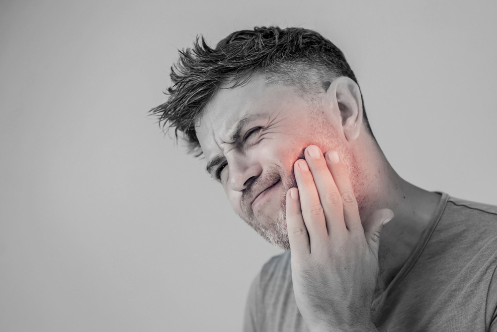 A man holding his jaw and having problems with it