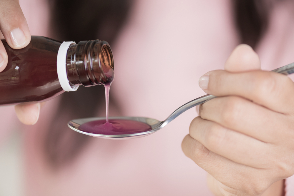 Woman pouring codeine in a spoon