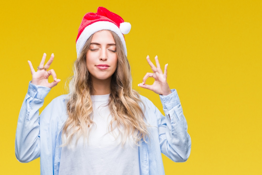 Beautiful young blonde woman wearing christmas hat over isolated background relax and smiling with eyes closed doing meditation gesture with fingers.