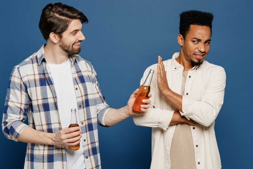 A guy declining an alcohol drink from a friend