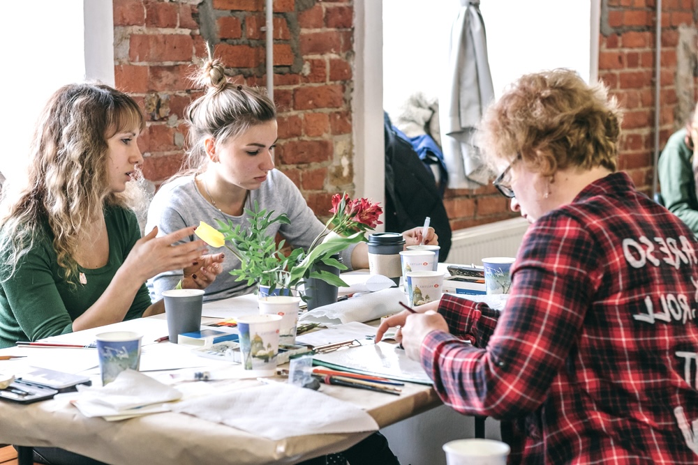 Group of people at the table at a painting class to boost their mental health