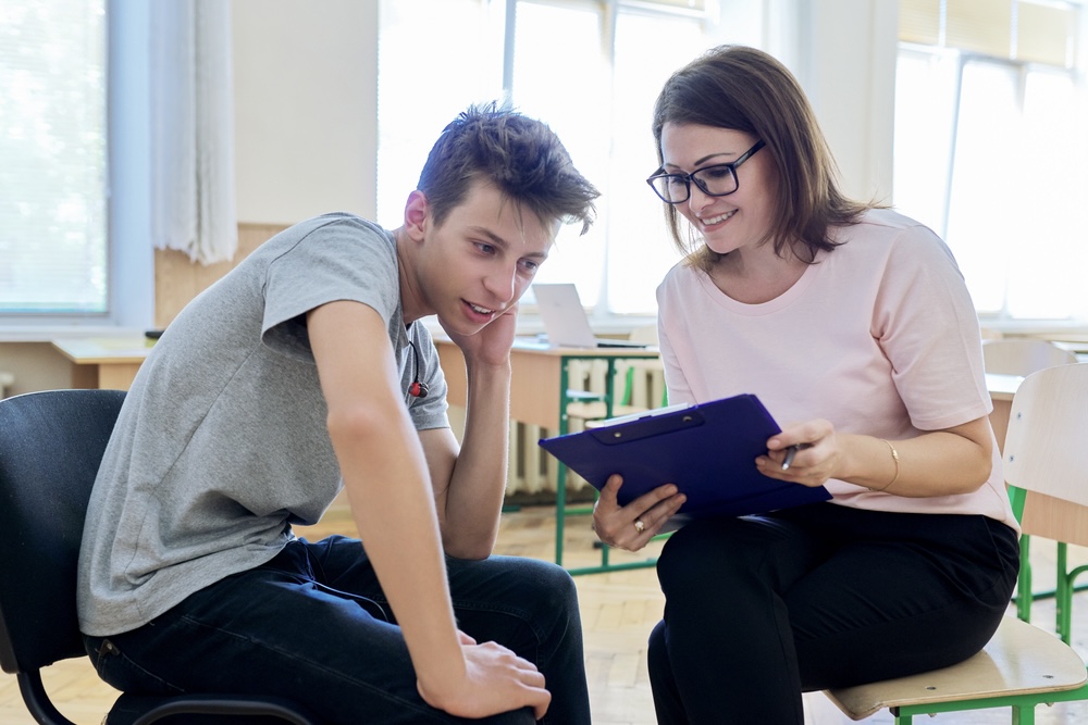 A teenage boy looking shy while talking to a professional counselor