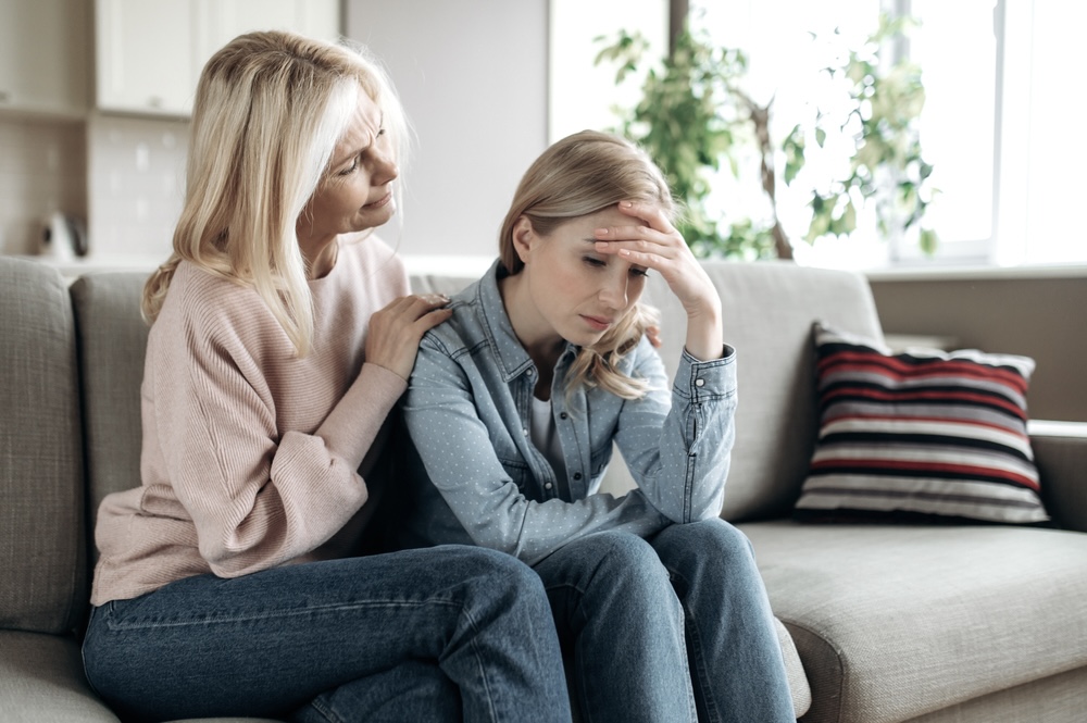 Mother comforting her daughter on the couch who told her she is in addiction recovery