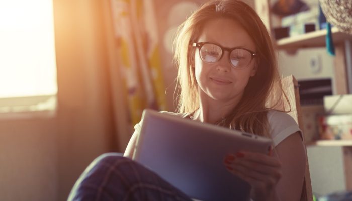 A woman wearing eyeglasses reading Thanksgiving addiction recovery quotes while sitting in a chair