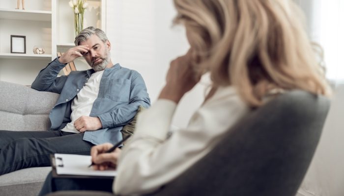 A troubled man suffering from substance abuse talking to a psychologist