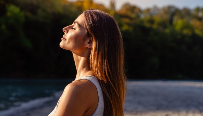 A woman with eyes closed while calmly and feeling the breeze