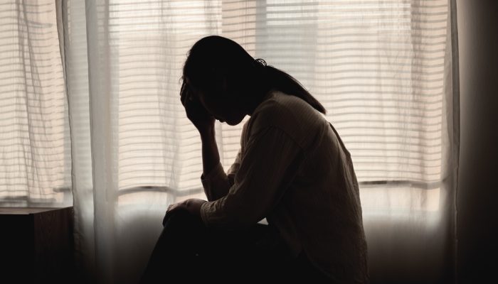 A woman suffering from cocaine addiction sitting in her bed feeling sad