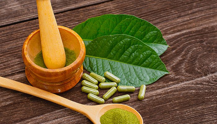 Kratom pills and powder on a wooden table