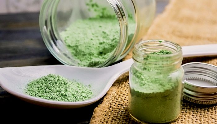 Kratom powder in a spoon and bottles