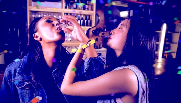 Two women in a bar drinking tequila shots